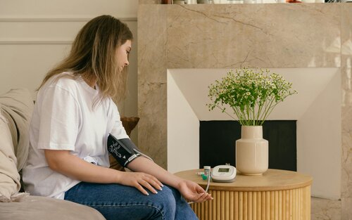 Une femme est assise sur une chaise et a un tensiomètre autour du bras.