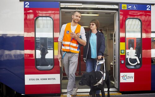 Ein Mitarbeiter der Bahnhofhilfe hilft einer Frau mit Sehbehinderung beim Aussteigen aus dem Zug. | © © SBB CFF FFS