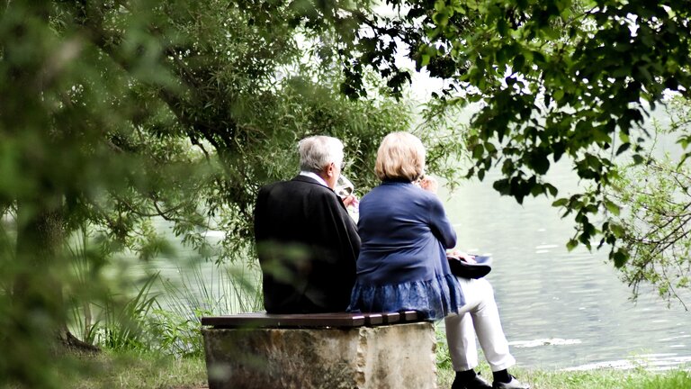 Un couple de personnes âgées est assis sur un banc au bord du lac.  | © unsplash