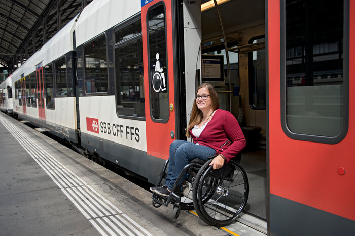 Eine Frau die mit ihrem Rollstuhl aus einem Zug der SBB fährt.