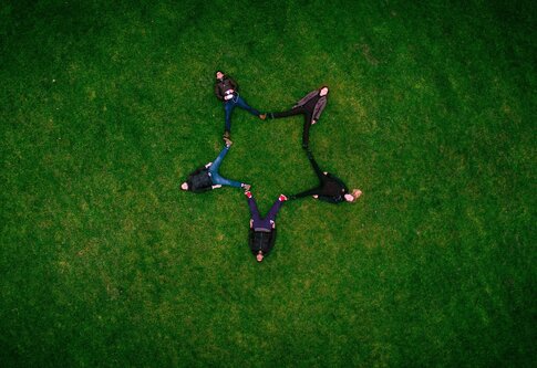 Cinq adultes s'allongent sur l'herbe et forment une étoile. | © pixabay
